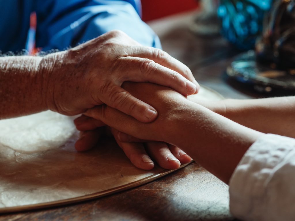 caregiver holding the hand of an elderly patient with dementia