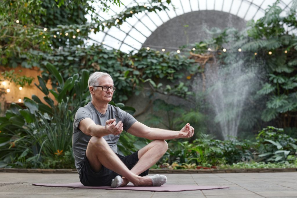 senior man outdoors with legs crossed on the floor doing a core exercise