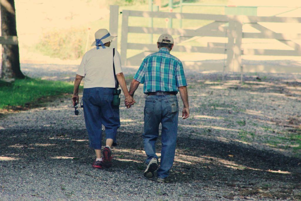 elderly couple holding hands wandering outside