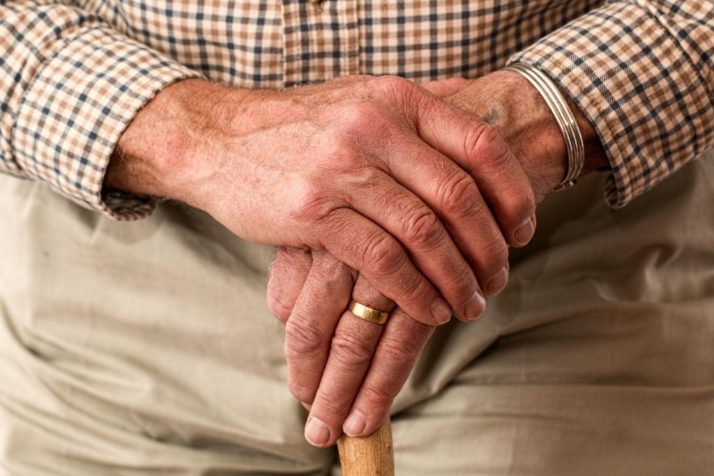 elderly dementia patient palms crossed over a walking cane
