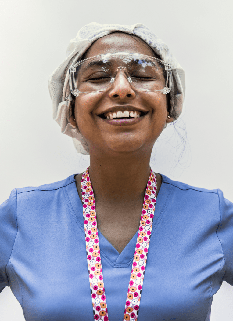 portrait shot of female health care provider wearing scrubs and smiling on a white background