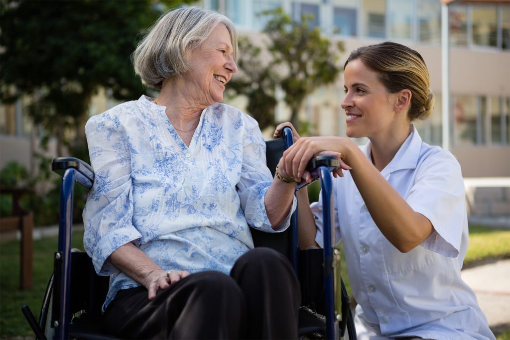 geriatrician conversating with elderly women on a wheel chair outdoors